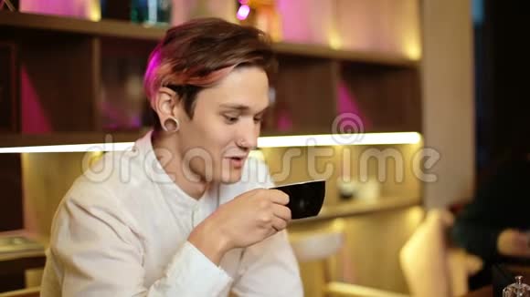 男人坐在咖啡馆里笑着笑着开心地拿着一杯黑咖啡手里拿着饮料视频的预览图