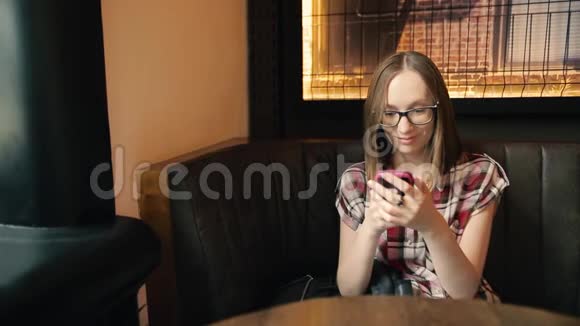积极的年轻女性在现代智能手机上阅读有趣的信息并大笑视频的预览图