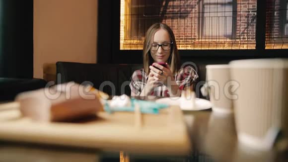 积极的年轻女性在咖啡馆内部的智能手机上阅读有趣的信息视频的预览图