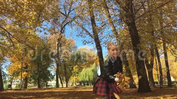 可爱的快乐学校女孩把落叶扔了起来在秋天的森林里玩美丽的女孩在玩视频的预览图