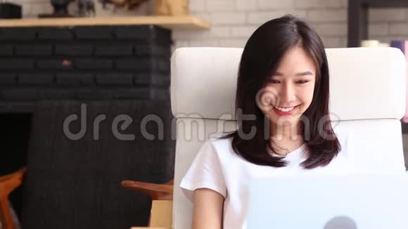美丽的肖像亚洲年轻女子在网上工作微笑着开心地笑着坐在客厅视频的预览图
