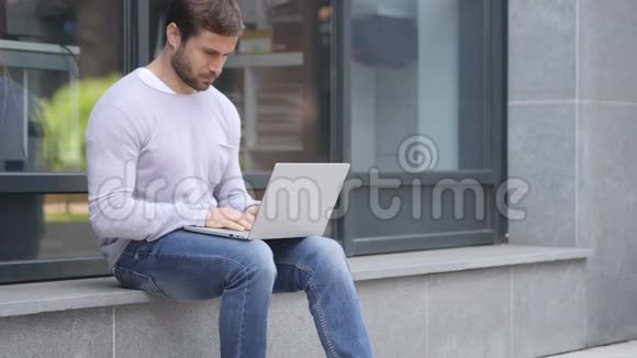 戴头巾的帅哥在办公室外坐着笔记本电脑视频的预览图