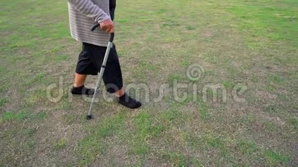 老年妇女用手杖在草地上行走的慢动作视频的预览图
