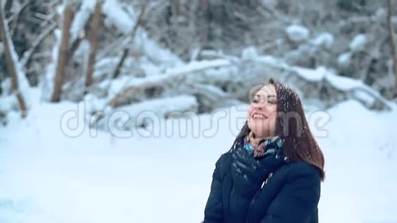 一个美丽的年轻女孩喜欢在寒冷的白雪覆盖的森林里散步视频的预览图