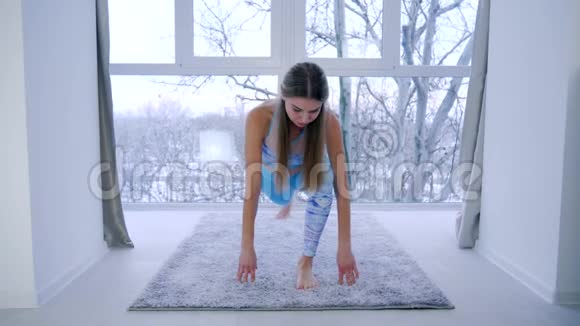 运动爱好灵活的女孩在家靠窗做瑜伽视频的预览图