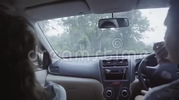 高加索男人和女人坐在车里在热带地区的农村公路上骑马视频的预览图