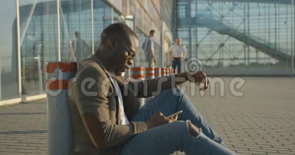 自信时尚的非洲男人的侧面肖像在通过手机交谈时进行情感交谈和手势视频的预览图