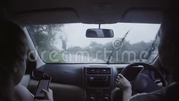 白种人男人和女人坐在车里在雨天骑在农村公路上视频的预览图