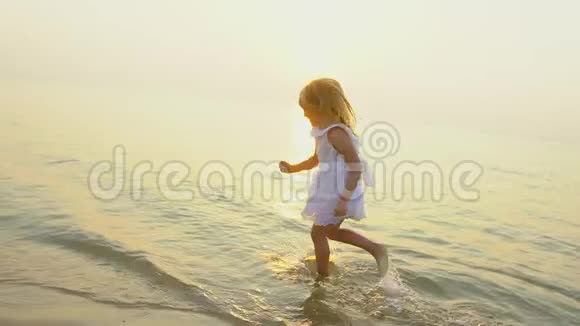 小女孩可爱的女孩在美丽的日落沙滩上奔跑在慢动作中度过快乐的假期孩子有视频的预览图