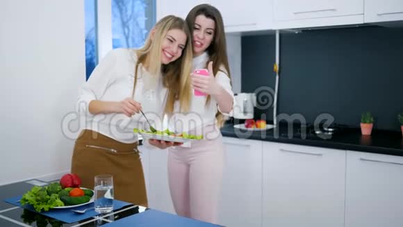 快乐的朋友们看着安卓系统上的照片手里拿着饭菜站在厨房里视频的预览图
