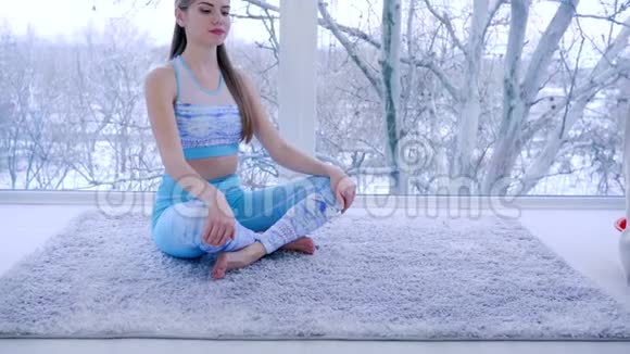 瑜伽课令人惊叹的女人在靠近窗户的房间里冥想时深深地呼吸视频的预览图