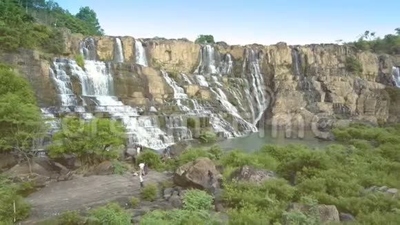 游客站在岩石上欣赏日落时的瀑布悬崖视频的预览图