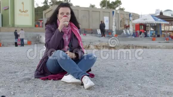 公共海滩上的女人她喝茶在很多人的背景下侧视图原始处理4k视频的预览图