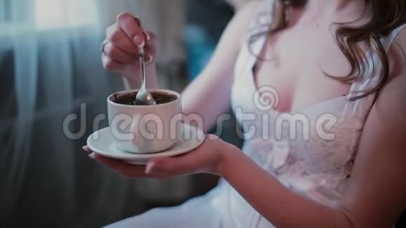 在理发师做新发型的时候一位穿着白皮诺伊的年轻女子正在喝咖啡视频的预览图