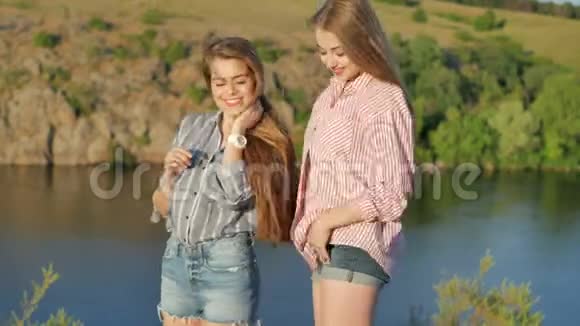 两个年轻女孩在河岸的摄像机上摆姿势视频的预览图