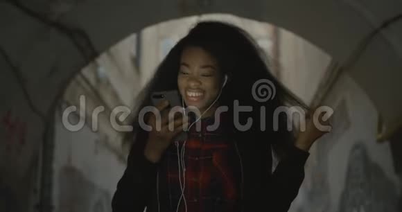 可爱的非洲女孩拿着手机的肖像4她正在跳舞正在听音乐视频的预览图