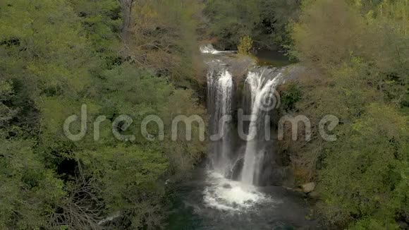 慢镜头无人驾驶飞机拍摄的西班牙多云间阴天森林一个漂亮瀑布视频的预览图