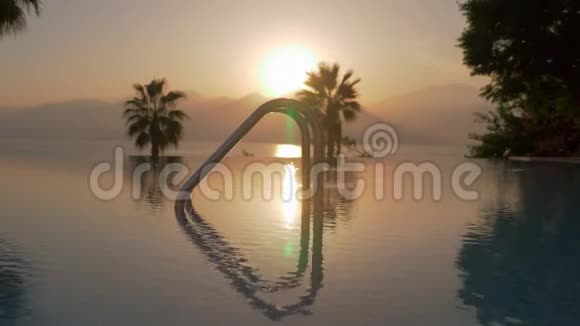 一张开放的游泳池和海边的日落的照片视频的预览图