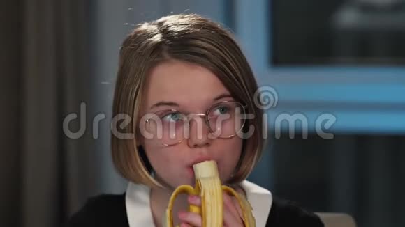 一个快乐的女学生正在吃香蕉午休和反射她在做作业特写视频的预览图