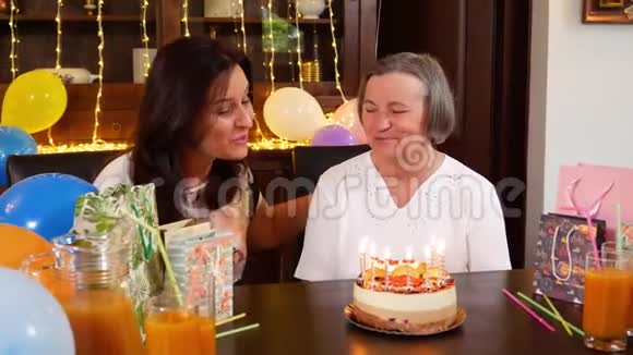 女儿和高年级妈妈在生日蛋糕或母亲节聚会上吹蜡烛视频的预览图