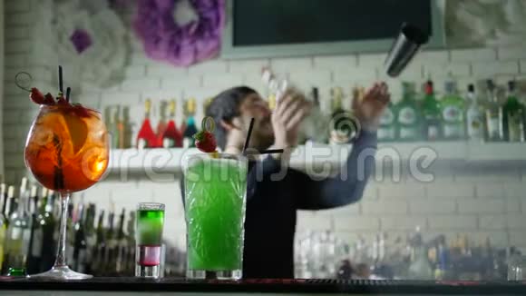 明亮的酒精饮料与新鲜草莓站在酒吧桌上和酒吧老板的背景表演杂耍视频的预览图