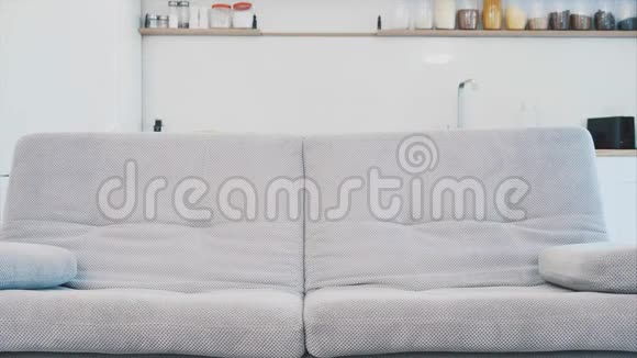 穿着浴袍的年轻女子坐在沙发上的房间里他坐在沙发上喝咖啡看电视视频的预览图
