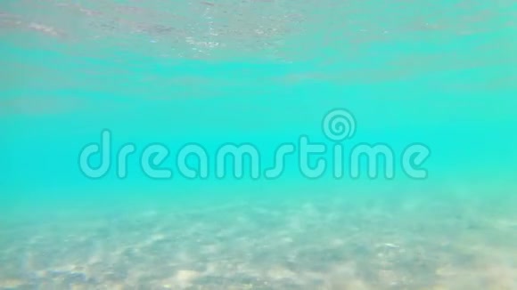 光波在沙滩上冲浪在晴朗的晴天带着茅草的海滩伞红海从下面看广角视频的预览图