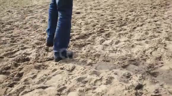 穿着蓝色牛仔裤的人走在波罗的海沿岸的沙滩特写镜头中视频的预览图