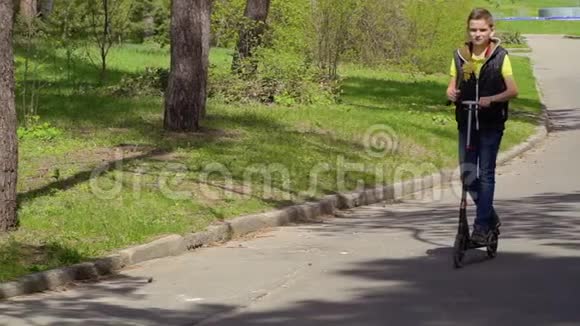 可爱的男孩带着水仙花的花在公园里踢滑板车上视频的预览图