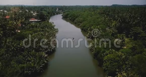 在热带绿树丛中的丛林荒野中在美丽宽阔的河流上无人机在小船上向前飞行视频的预览图