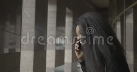 这位可爱的非洲女孩在街上通过手机聊天时大笑的情感肖像4K录像视频的预览图