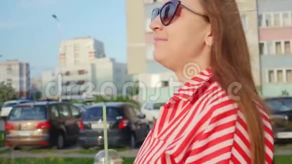 穿红色衣服的孕妇在等孩子女人喝橙汁走在城市里的概念视频的预览图