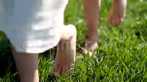 一个夏天两个穿着白色亚麻衣服的女孩沿着一片绿色的草地散步身体部位视频的预览图