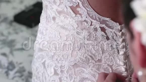 伴娘和新娘的母亲帮助新娘关闭花边婚纱上的纽扣视频的预览图