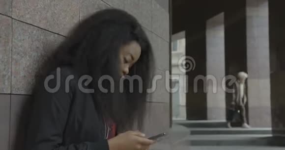 年轻漂亮的非洲女孩在耳机里享受音乐跳舞和通过手机发短信的侧面画像视频的预览图