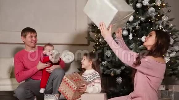 孩子们和父母坐在新年树和礼物堆附近视频的预览图