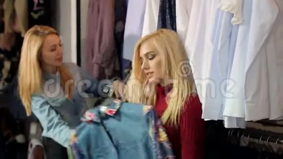 两个时髦的金发女孩在一家大型服装店挑选衣服视频的预览图