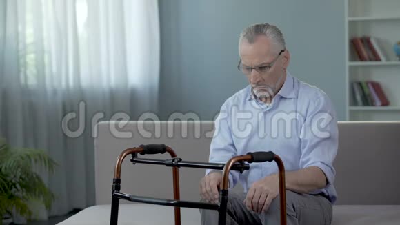 老人坐在沙发上看着站在他面前的行走架视频的预览图
