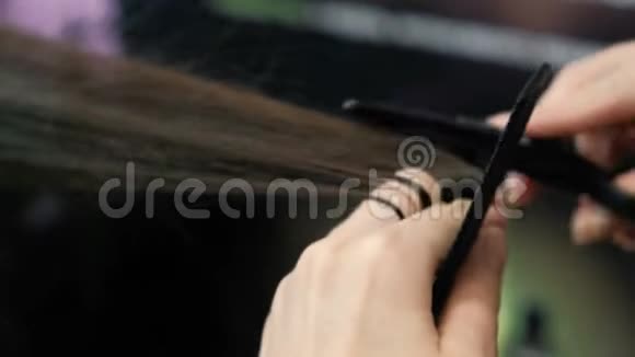 理发师他的手剪着长长的黑发头发热剪刀视频的预览图