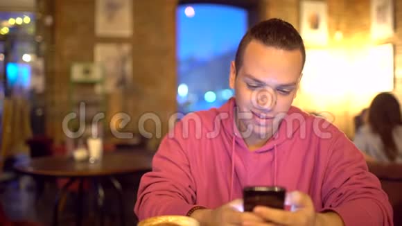 西班牙裔年轻人使用移动电话在舒适的咖啡店西班牙裔迷人的微笑肖像视频的预览图