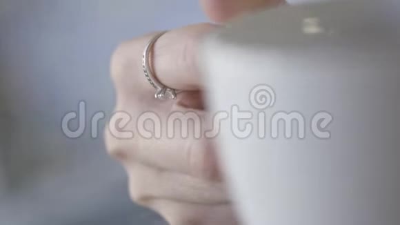 白色杯子的漂亮手握柄的特写行动温柔的手与美丽的银环和石头保持视频的预览图