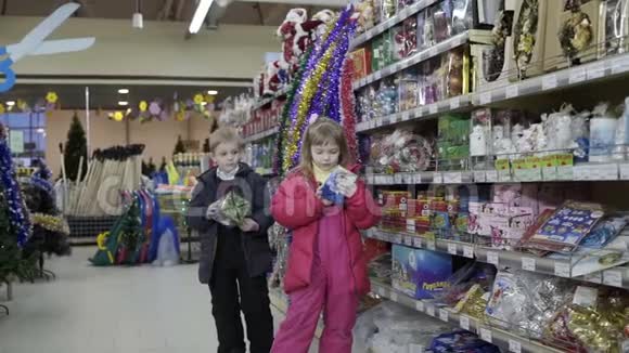 小可爱的女孩和男孩选择在购物中心装饰圣诞树视频的预览图