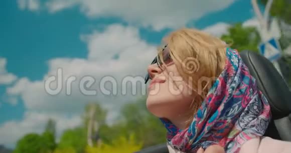 华丽时尚的金发女人在敞篷车里开车的肖像3她在搬家时戴着太阳镜和围巾视频的预览图