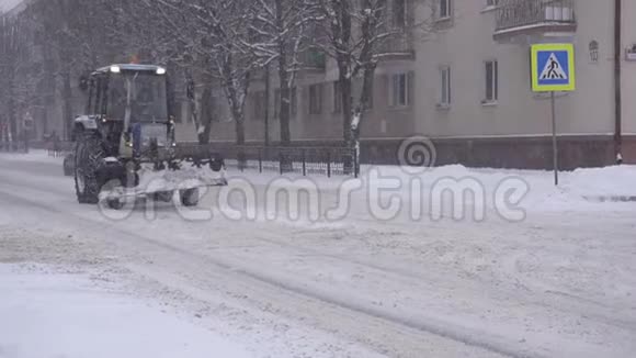 一辆旧拖拉机用来除雪骑到一个冬天的城市降雪慢动作视频的预览图