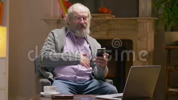 有胡子的老人在看教育网站时使用智能手机视频的预览图
