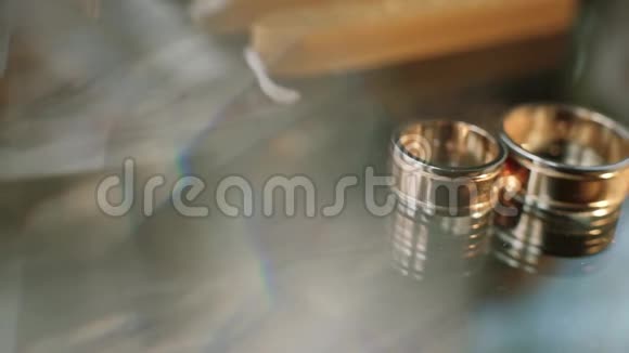 两个金色的结婚戒指躺在一张桌子上装饰上闪耀着光接近宏观光的传输视频的预览图