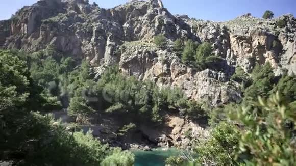 在蓝天上覆盖着绿色植被的山景艺术岩石悬崖上覆盖着树木和灌木视频的预览图