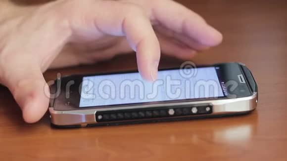 男人手指用触摸屏触摸智能手机躺在桌子上视频的预览图