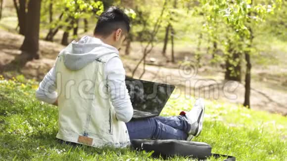 在公园里用笔记本电脑微笑的种族人士视频的预览图