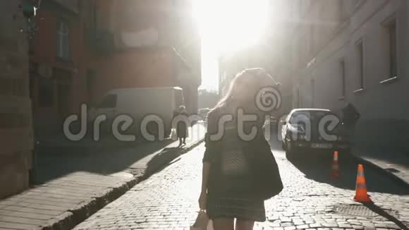 这位穿着漂亮衣服的迷人年轻女孩正在阳光明媚的城市街道上散步抚摸着她的头发视频的预览图